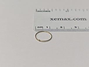 A Dynaflex BRASS SEPARATING WIRE .020 ring, approximately 1 cm in diameter, is shown on a white surface next to a ruler marked in centimeters and inches.