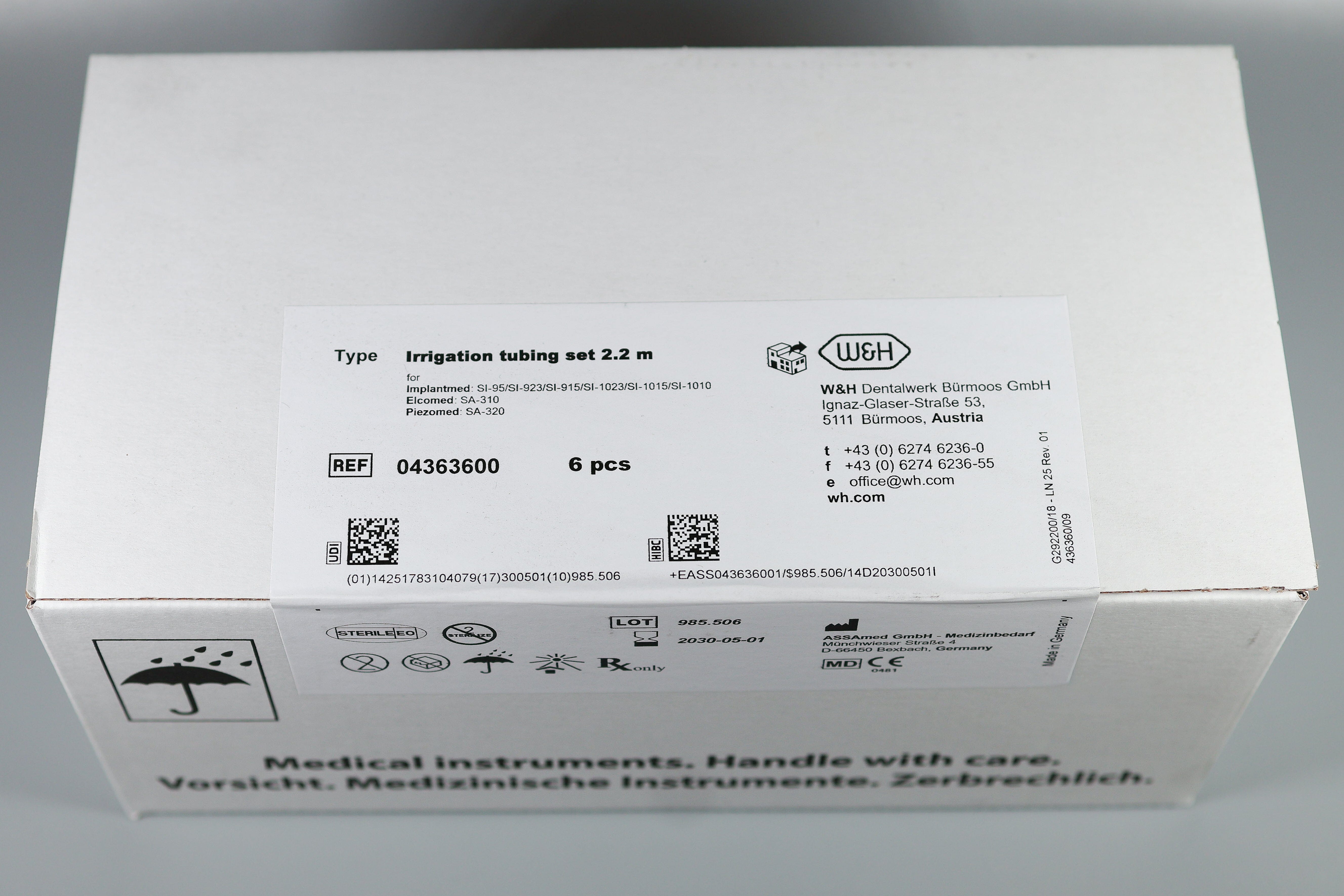 White box labeled "W&H Disposable Irrigation Tubing for Implant & Surgical Motors Pk/6." Sticker notes 6 pieces, W&H branding, medical symbols. English and German text: "Medical instruments. Handle with care.