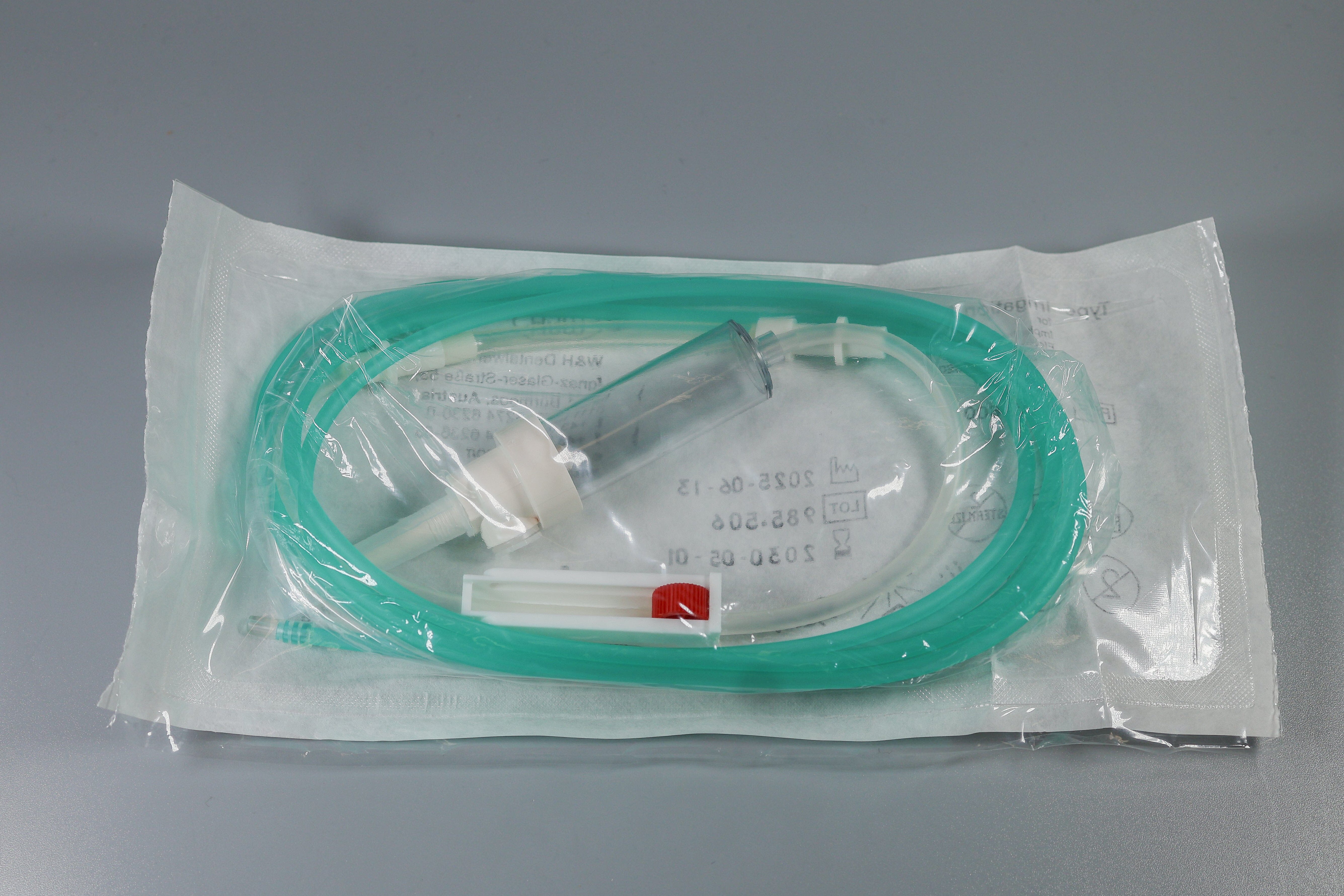 The W&H Disposable Irrigation Tubing for Implant & Surgical Motors (Pk/6) features a green tube, clear drip chamber, and white connector, sealed in a transparent pouch. Brand: W&H.