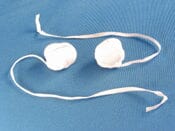A pair of white Post-Op Pack – Retrievable Radiopaque Gauze Sponges with 10″ tails, lying on a blue textured surface.