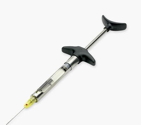 The Ronvig Aspi-Ject® Self-Aspirating Syringe, featuring a metal handle and black finger grips with an attached cartridge and fine needle, is shown on a white background for local anesthesia delivery.