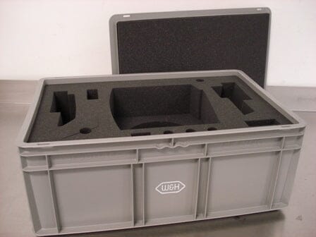 The W&H Impex transportation case is a gray plastic box with a removable lid and custom black foam inserts, featuring the W&H logo. It securely holds complete units or accessories and is ideal for transporting or storing W&H products.