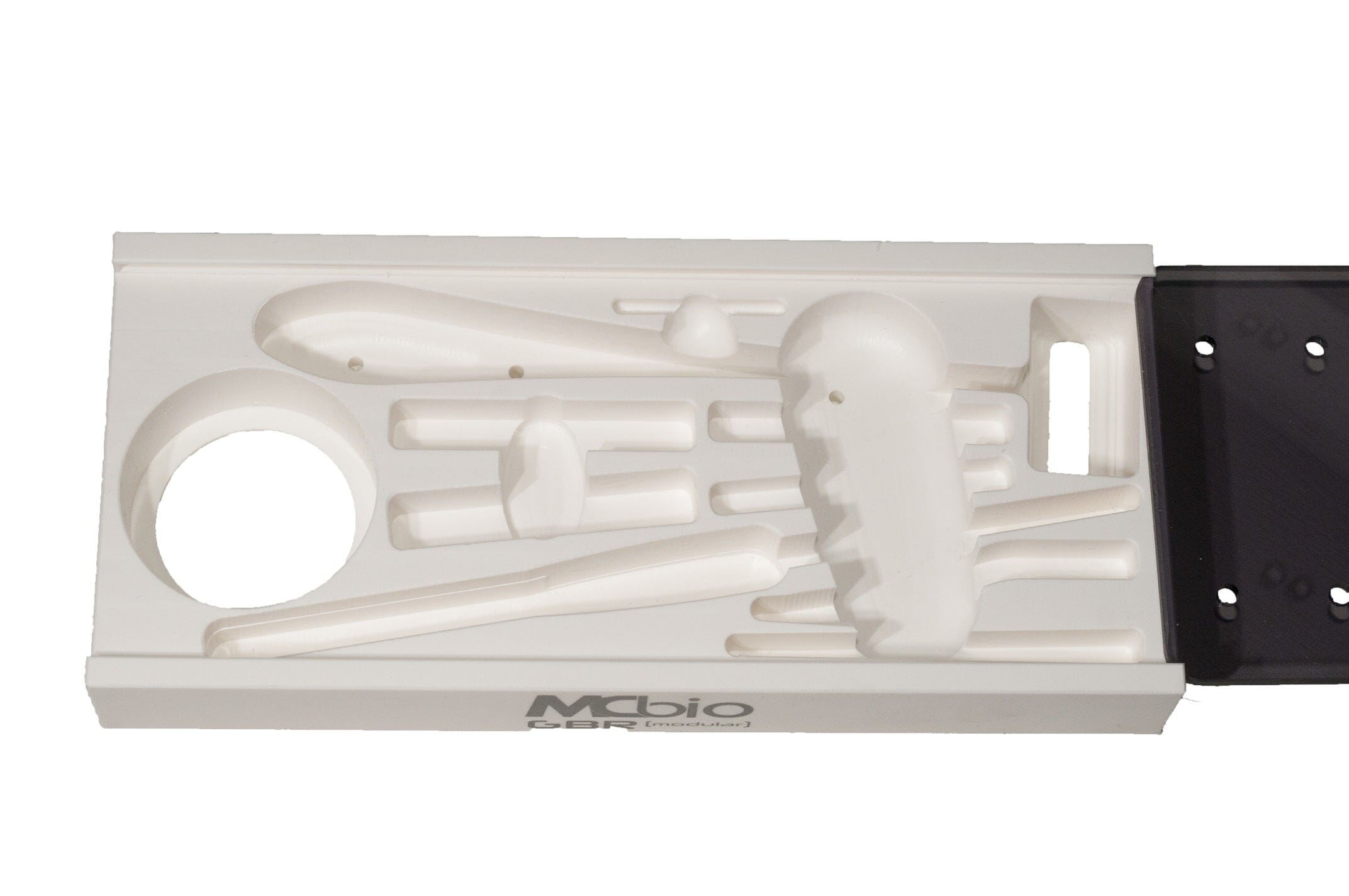 The McBio Tray - STS Bone Scraper Set is a white plastic tray with indented shapes, including circles, rods, and a large abstract form, designed to hold bone scraper tools or similar scientific instruments.