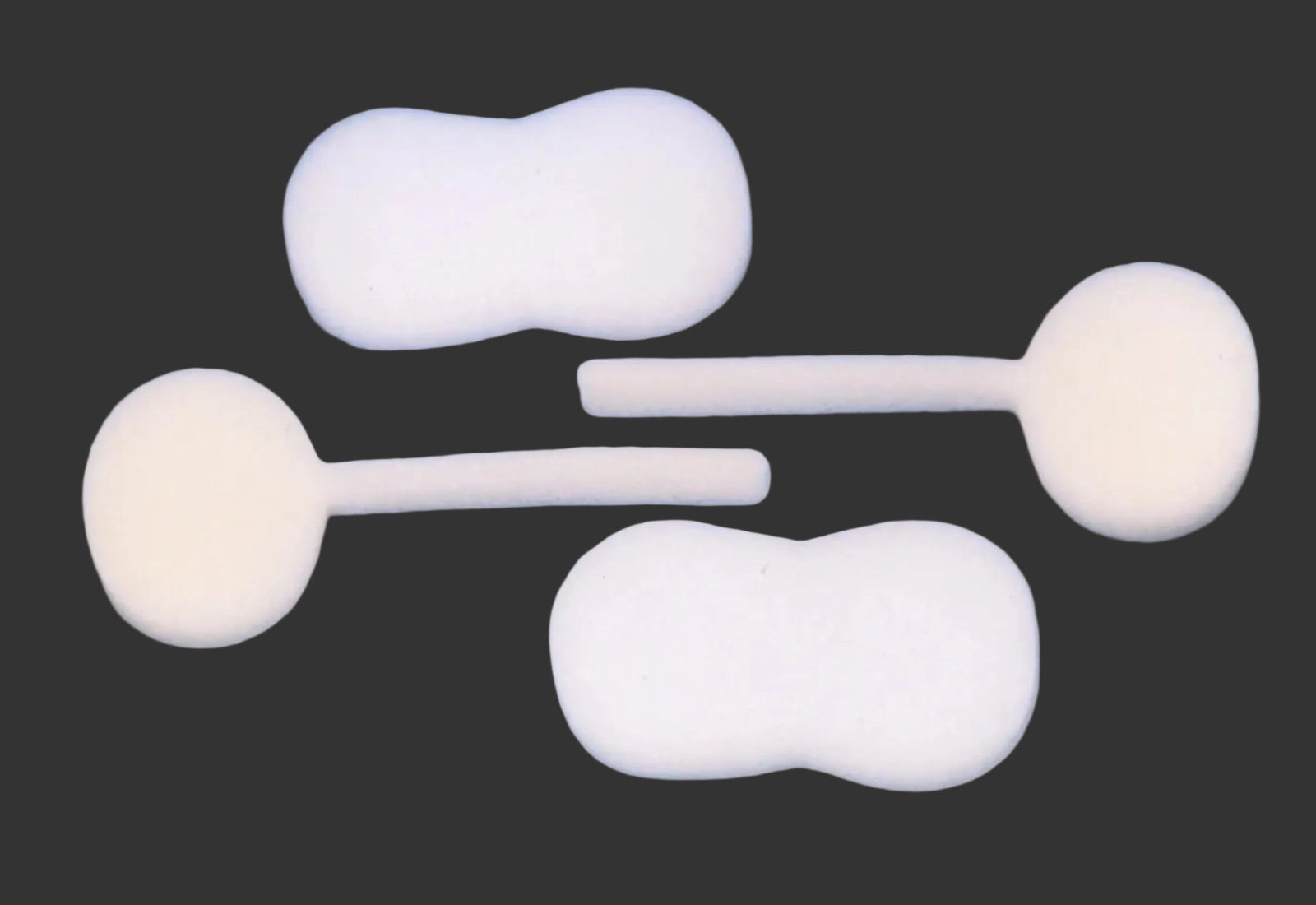 Picture of C-Sponge  3  with tail, and C-Sponge 4 peanut shaped against a grey surface