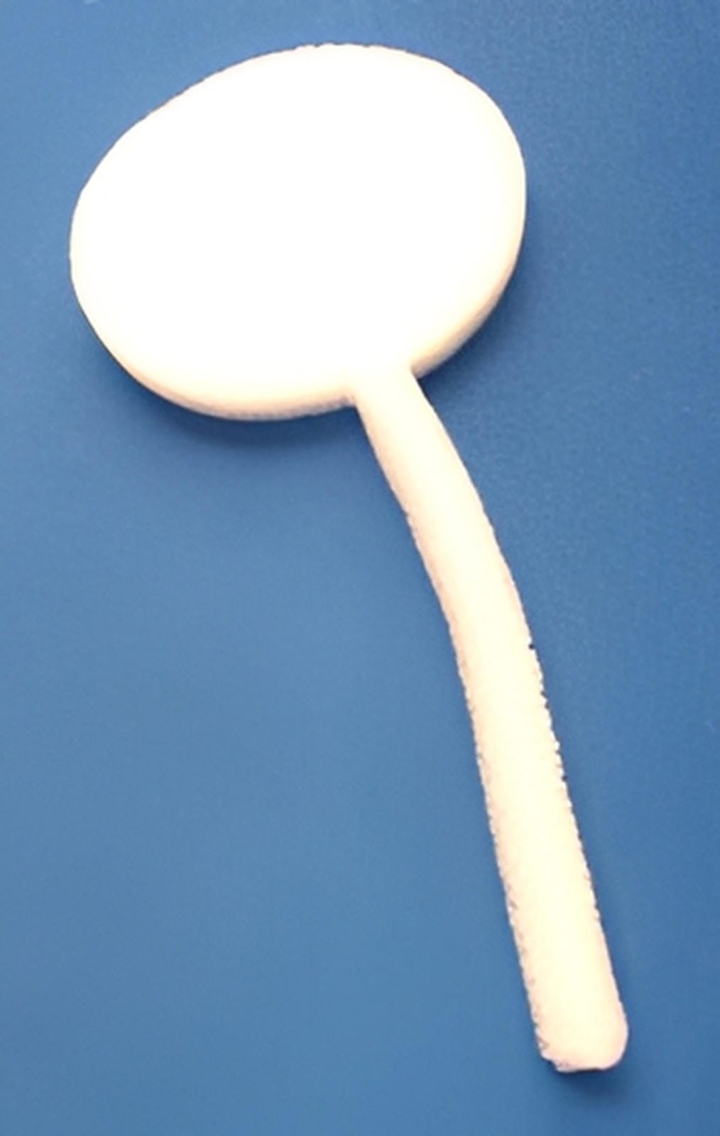 A C-Sponge III Surgical Throat Pack by Xemax, a white round polyurethane foam with a long retrieval tail, is shown on a blue surface.