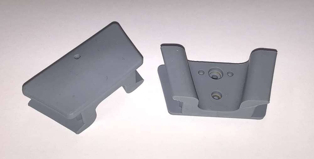 Two grey silicone Mouth Prop - Edentulous by DCI rests on a white surface—one flat, one upright—showing its curved edges, visible mounting holes, and autoclavable design.