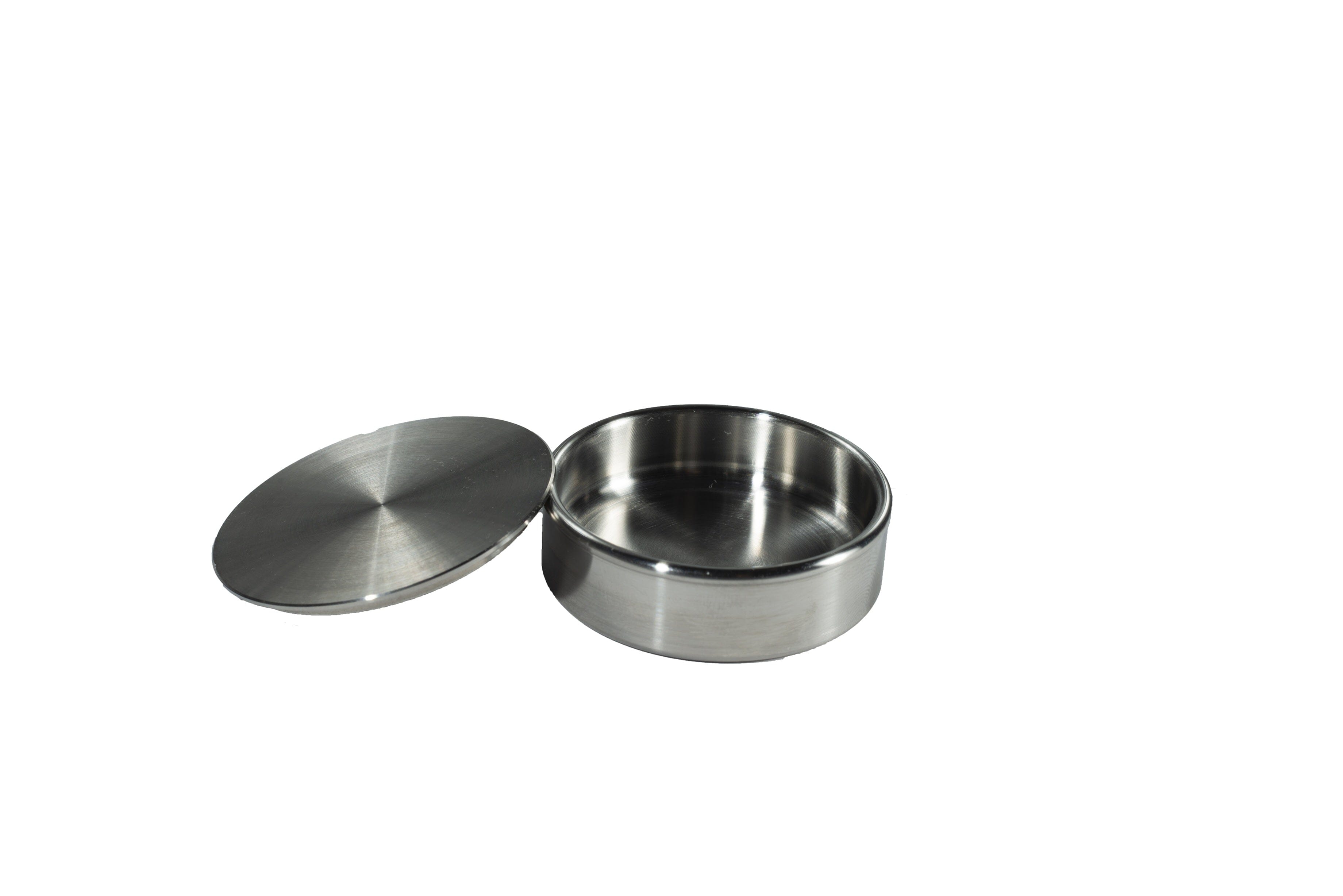 The Xemax Bone Graft Container & Lid Set – Stainless Steel is shown open and empty, with the matching lid placed beside it on a white background.